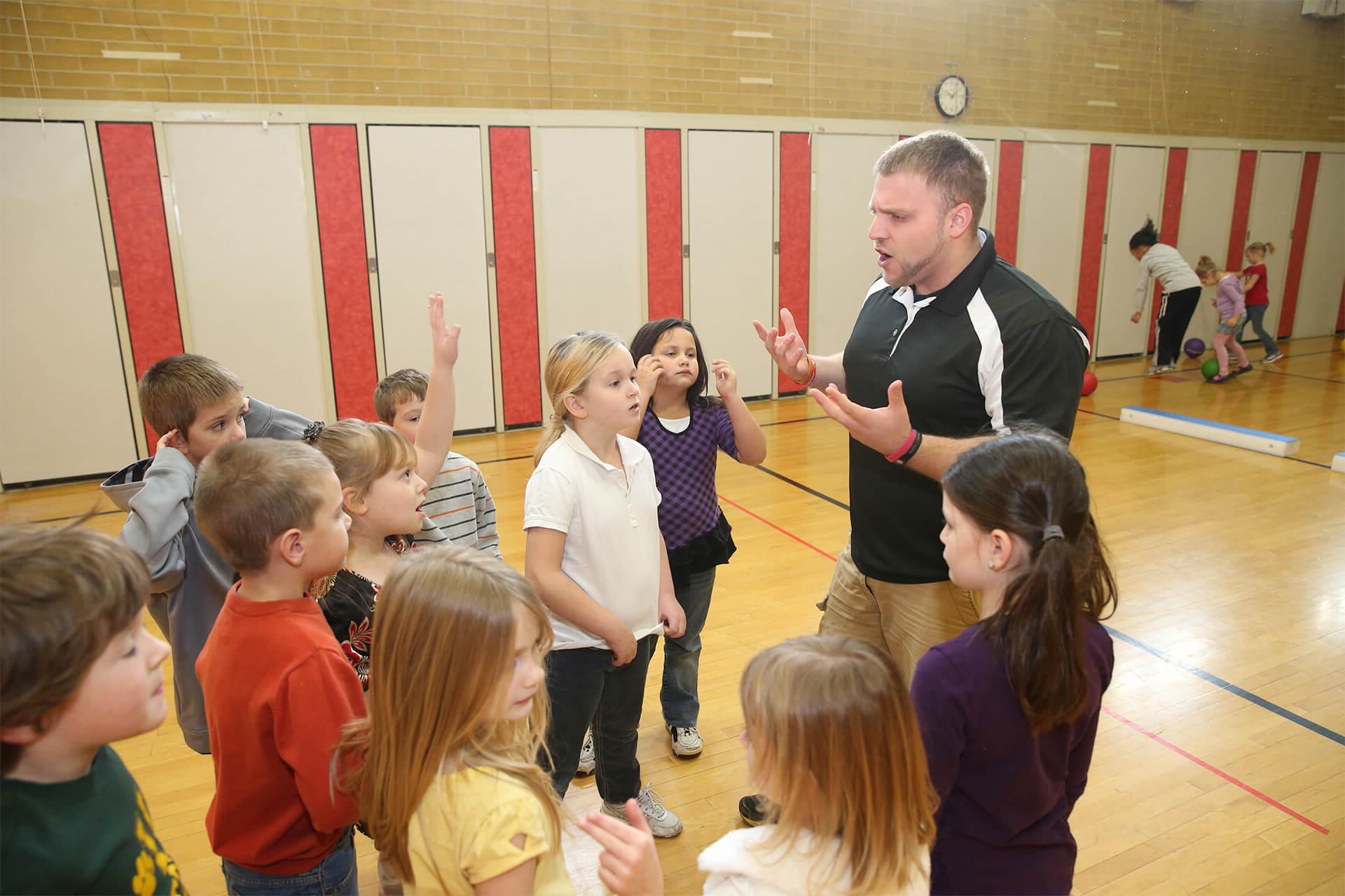 一位体育老师在体育馆里对一群孩子讲话